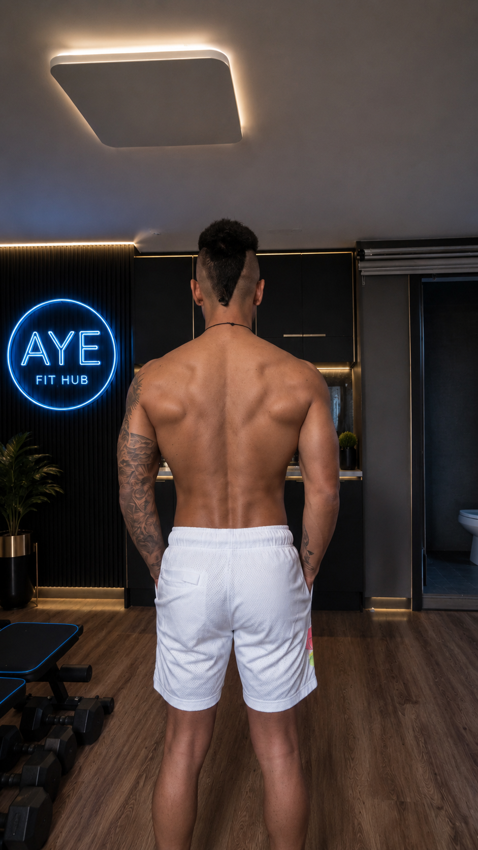 AYE Fit Hub training photo — back pose in front of the AYE Fit Hub neon studio sign